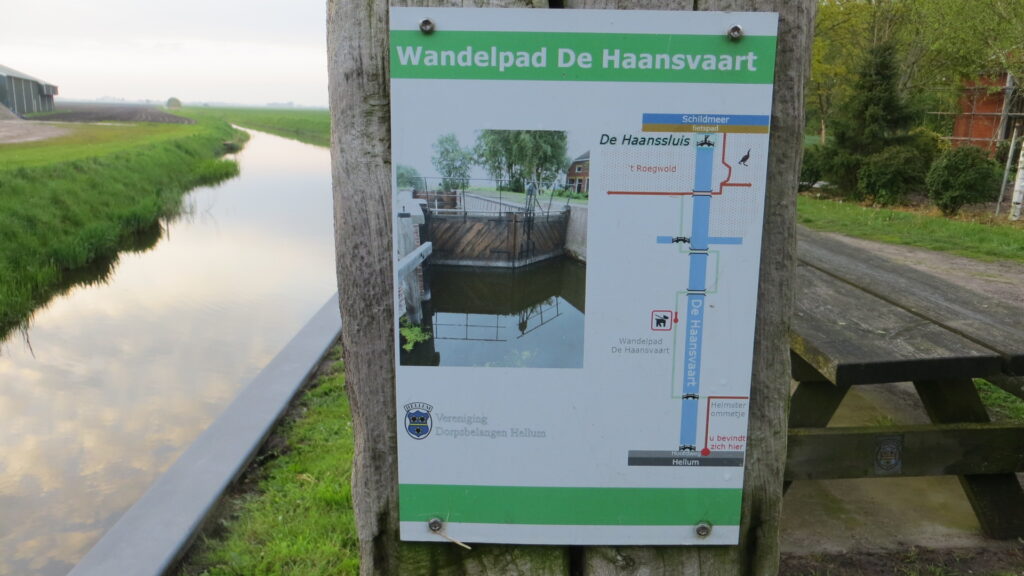 Beknopte weergave route wandelpad De Haansvaart op bordje bij de brug in het dorp